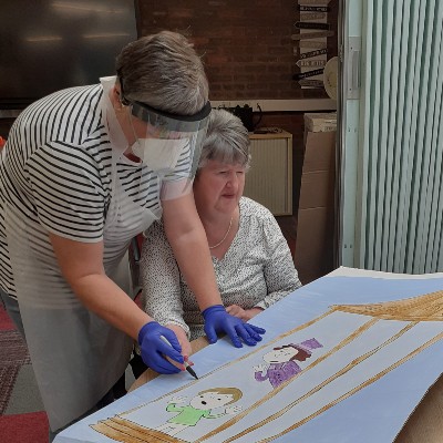 Carer helping service user draw a picture